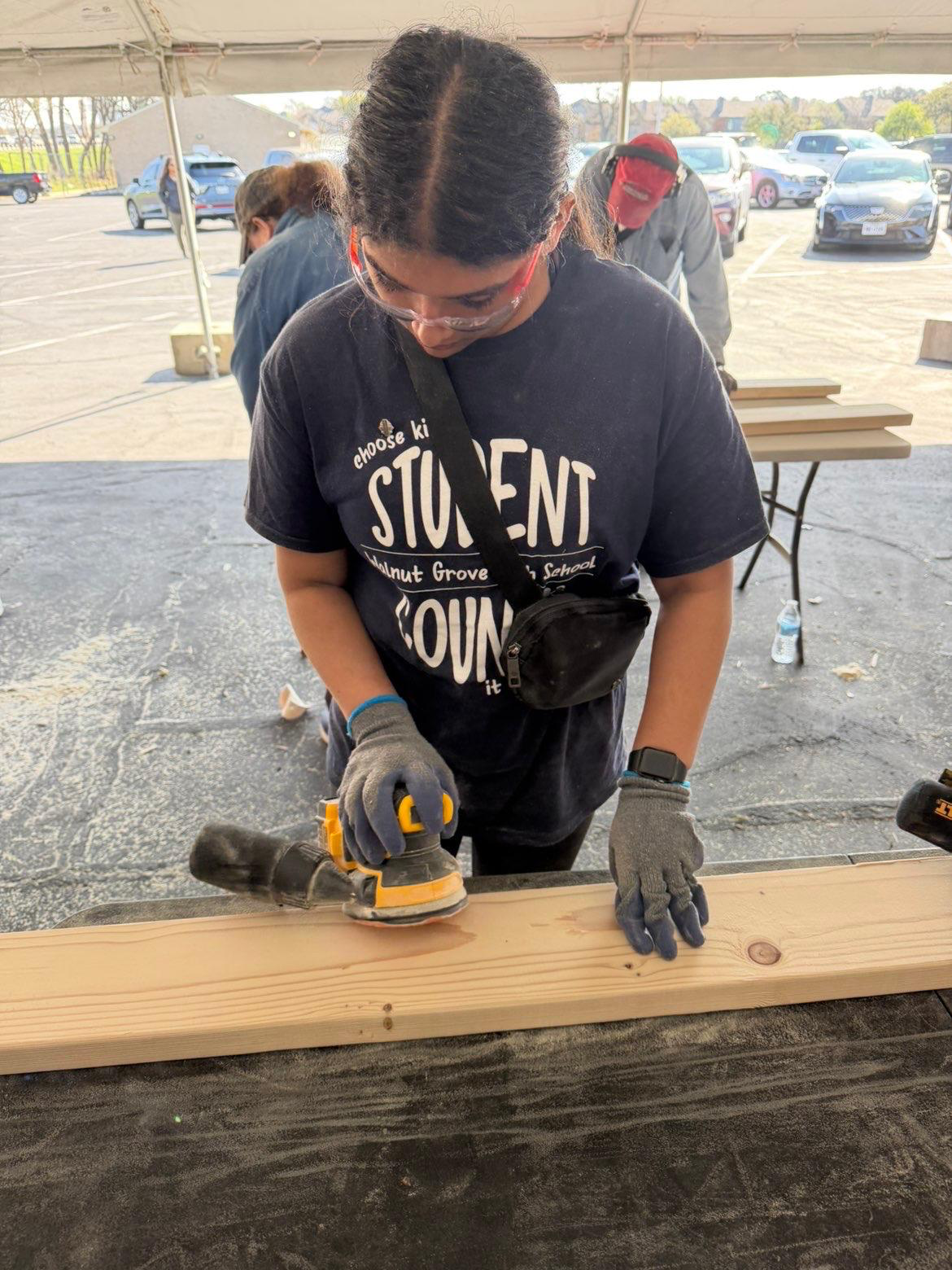 Sanding a wooden bed component during a volunteer project
